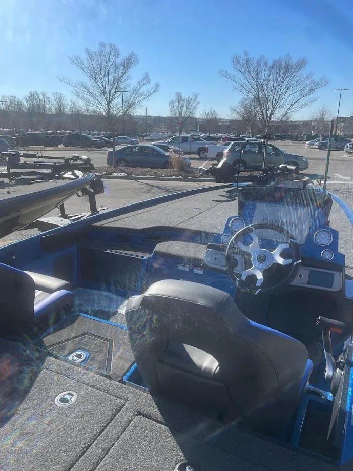 Slide: The Image of 2025 Nitro Z20 XL boat interior with steering wheel, parked in a sunny lot. - 1