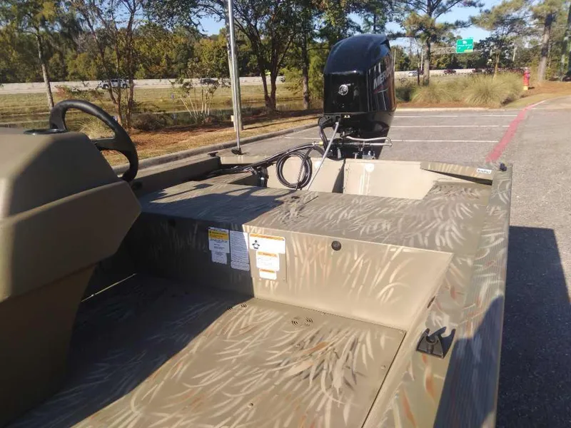 Slide: The Image of 2025 Tracker Grizzly 1648 SC boat with camouflage design in a parking lot. - 10