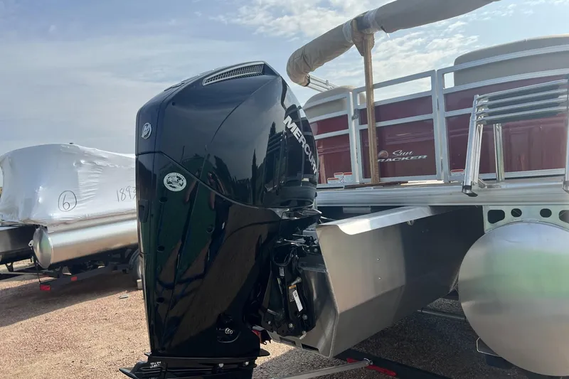 Slide: The Image of 2025 Sun Tracker Party Barge 22 XP3 with Mercury outboard motor, docked outdoors. - 2