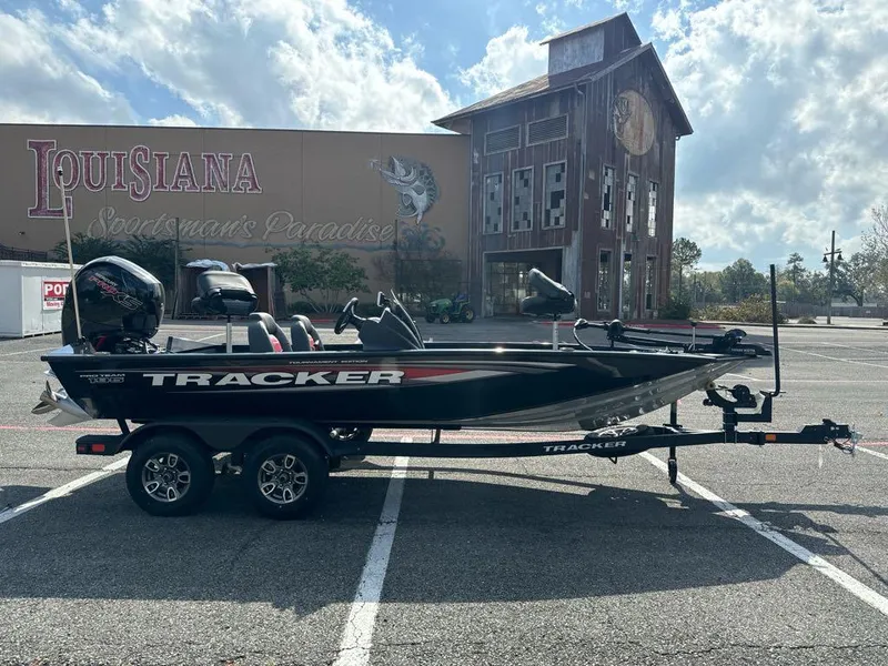 Slide: The Image of 2025 Tracker Pro Team 195 Tournament Edition boat in parking lot, Louisiana Sportsman's Paradise backdrop. - 2
