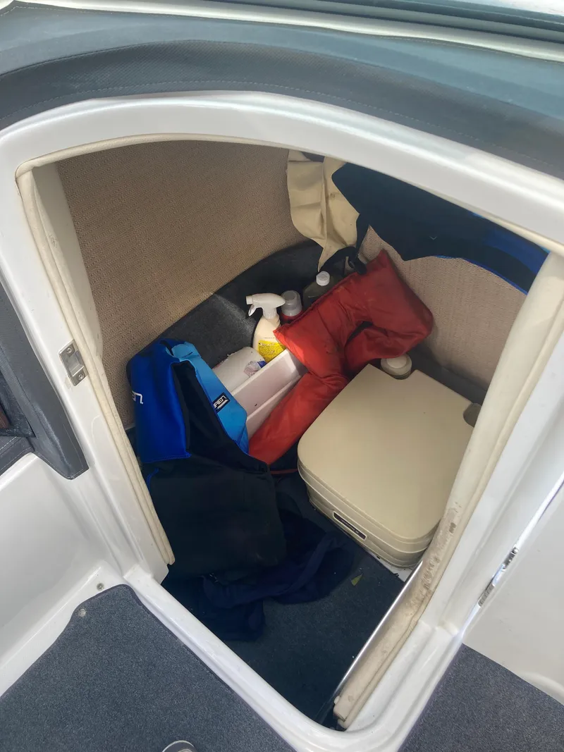 Slide: The Image of 2013 Cobalt 24SD boat storage area with life jackets and cleaning supplies. - 16