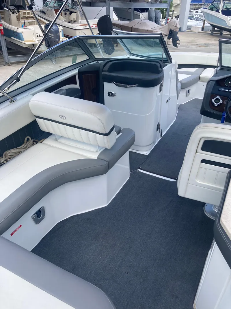 Slide: The Image of 2013 Cobalt 24SD boat interior with seating and dashboard, docked in a marina. - 26