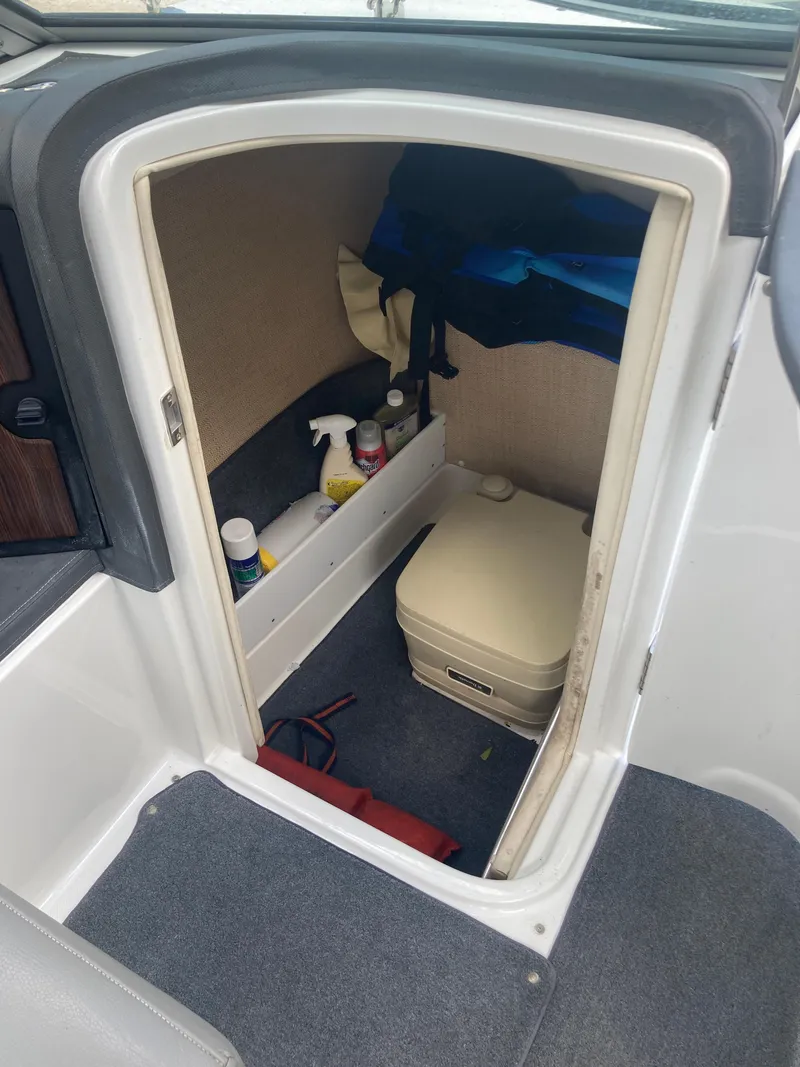 Slide: The Image of 2013 Cobalt 24SD boat interior storage with cleaning supplies and portable toilet. - 28