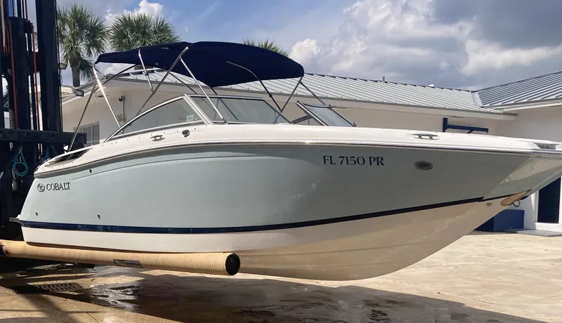 Slide: The Image of 2013 Cobalt 24SD boat with blue canopy, docked outdoors under a cloudy sky. - 5