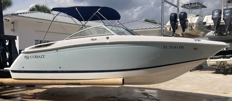 Slide: The Image of 2013 Cobalt 24SD boat with blue canopy, docked outdoors. - 8