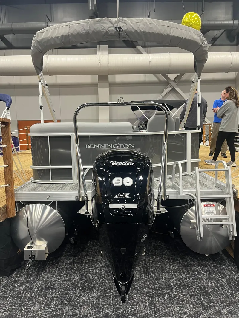 Slide: The Image of 2025 Bennington S Line pontoon boat with Mercury 90 engine displayed indoors. - 2