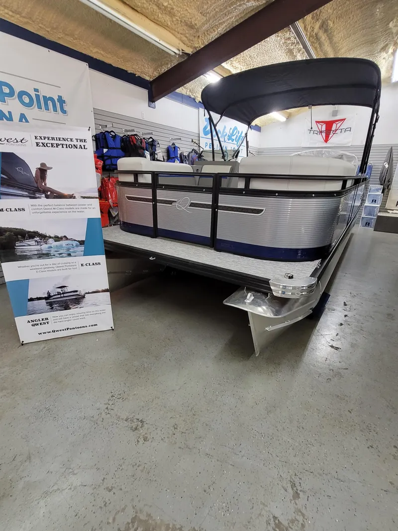 Slide: The Image of 2025 Quest 22 LE pontoon boat displayed in showroom with promotional banners. - 1