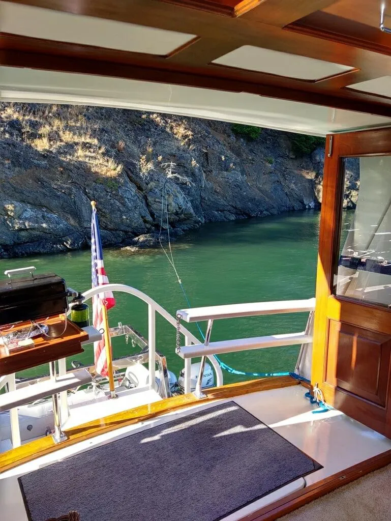Slide: The Image of 1971 Matthews Custom Pilothouse Motor Yacht interior with scenic water and rocky shoreline view. - 11