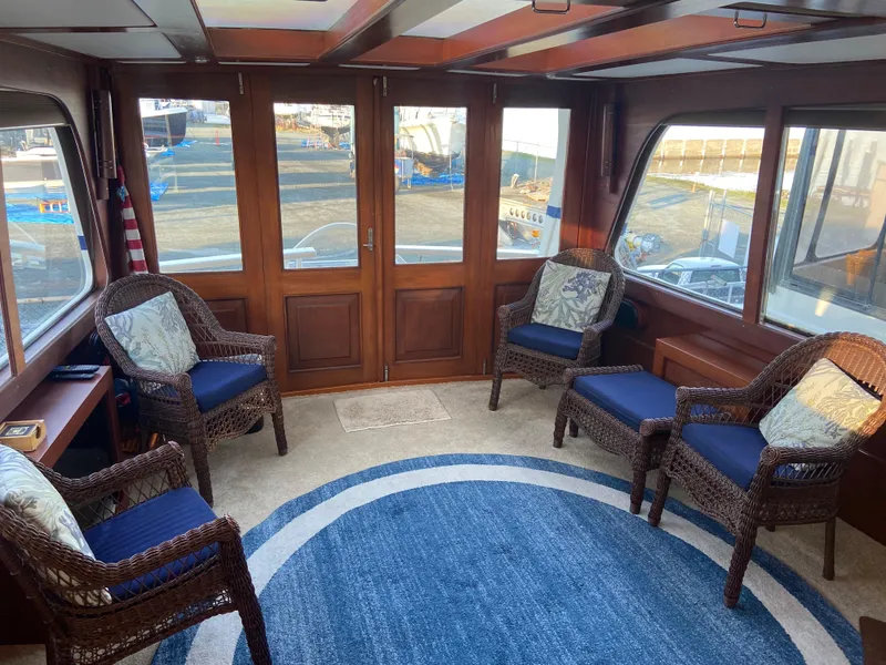 Slide: The Image of Interior of 1971 Matthews Custom Pilothouse Motor Yacht with wicker chairs and blue rug. - 13