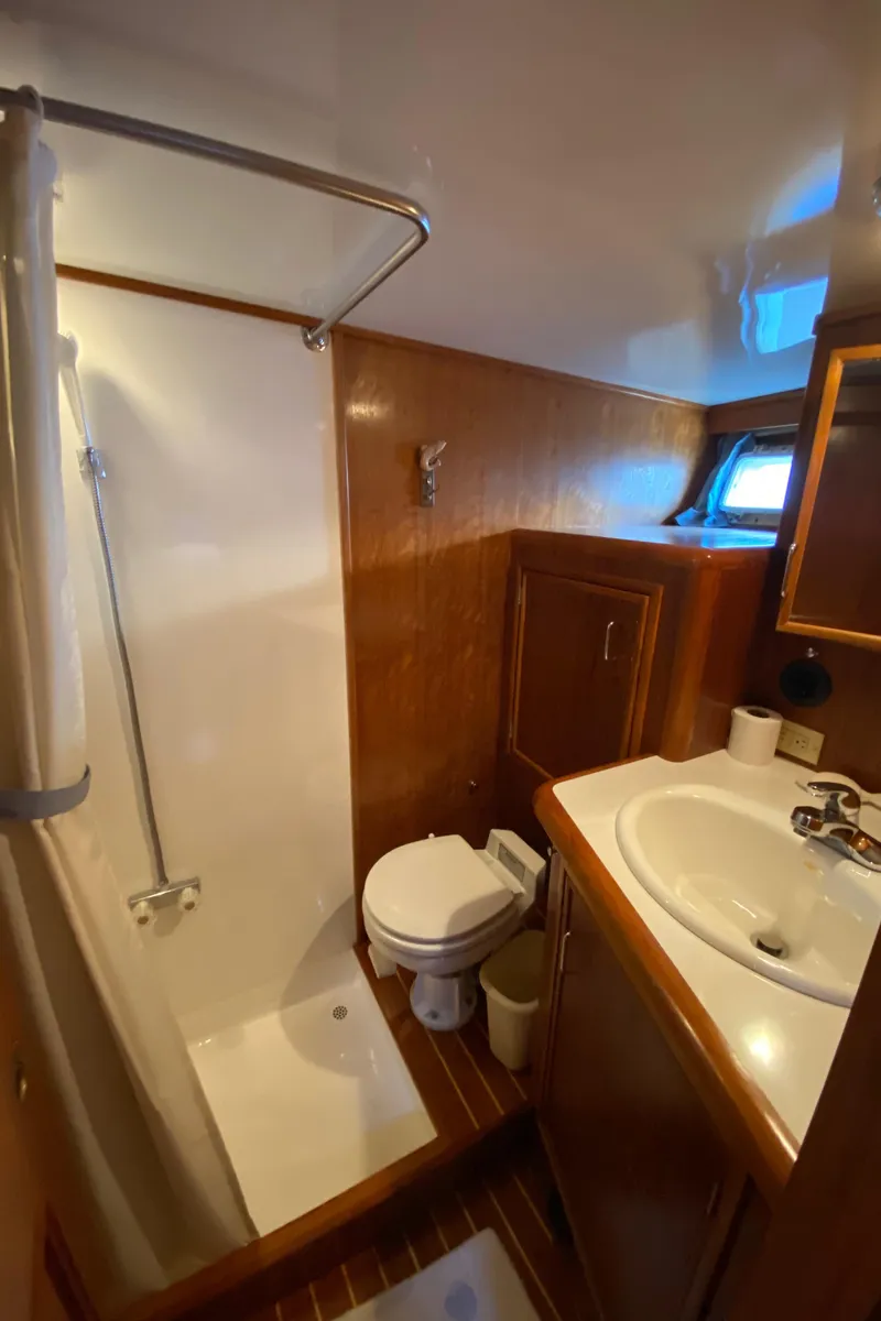 Slide: The Image of 1971 Matthews Custom Pilothouse Motor Yacht bathroom with shower, sink, and wooden cabinetry. - 27