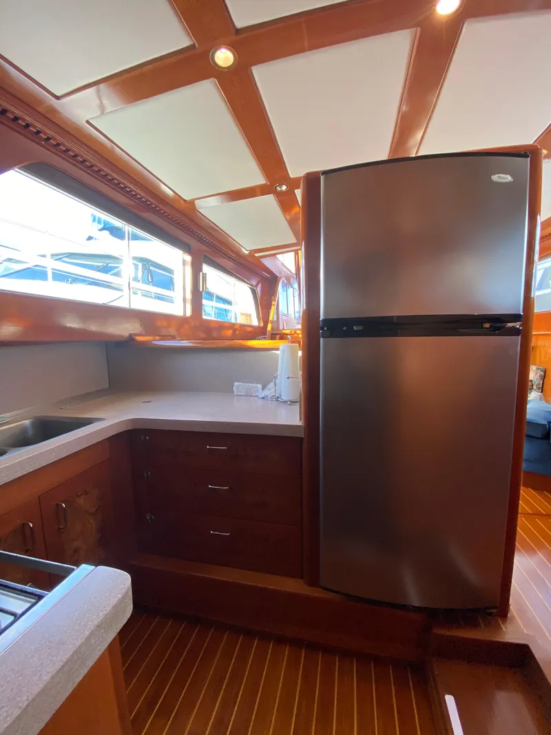 Slide: The Image of 1971 Matthews Custom Pilothouse Motor Yacht kitchen with stainless steel fridge and wooden cabinetry. - 37