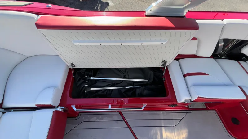 Slide: The Image of 2019 MasterCraft X24 boat interior with open storage compartment, red and white seating. - 22