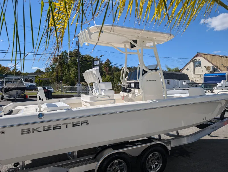 Slide: The Image of 2025 Skeeter SX 2550 Family boat on trailer under palm leaves. - 7
