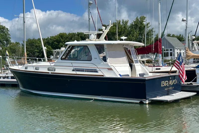 Slide: The Image of 2005 Sabre 42 Hardtop Express yacht docked in a marina, featuring a sleek design and American flag. - 1