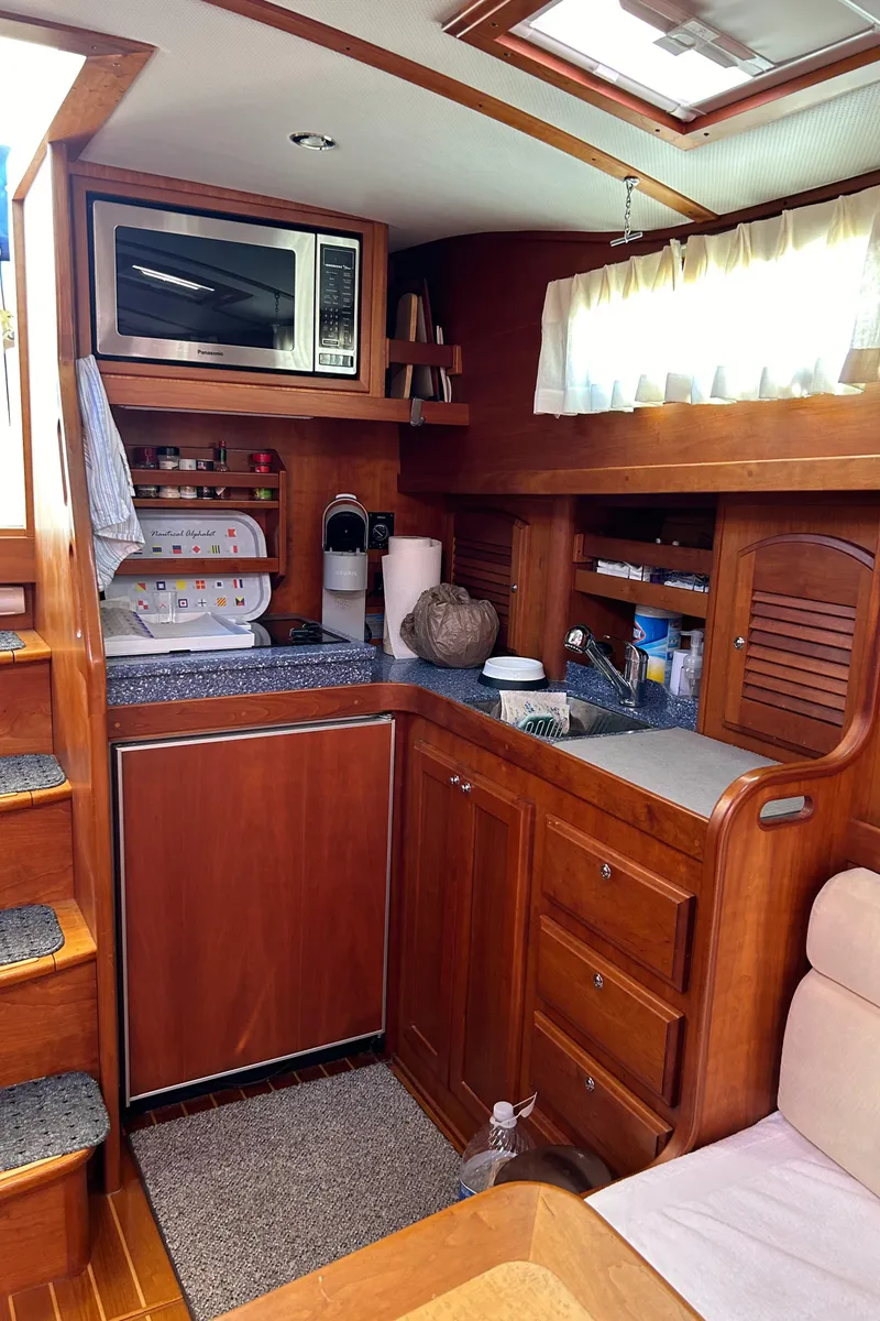 Slide: The Image of 2005 Sabre 42 Hardtop Express yacht interior kitchen with wood cabinetry and modern appliances. - 23