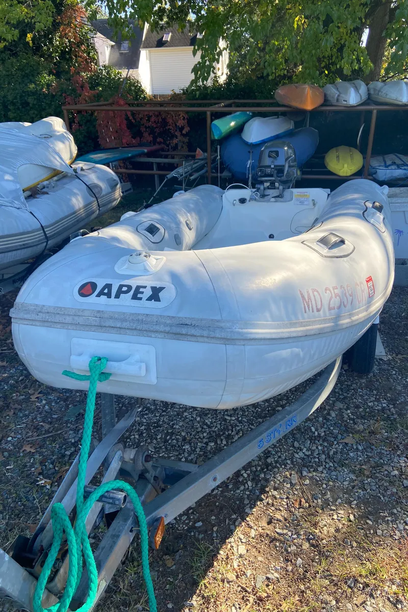 Slide: The Image of Inflatable Apex boat on trailer, surrounded by other boats and equipment. - 43
