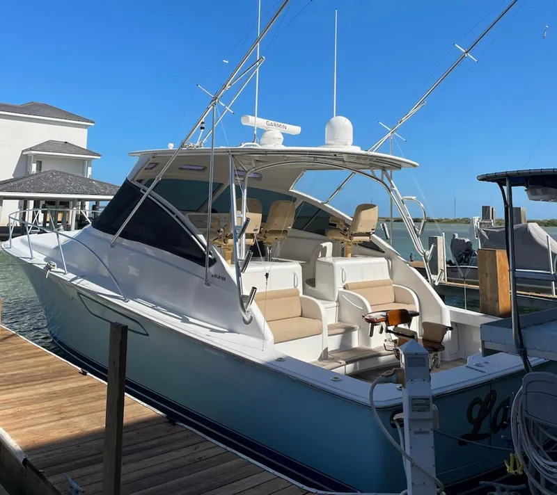 Slide: The Image of 2012 Viking 42 Open yacht docked, featuring spacious seating and fishing equipment. - 26