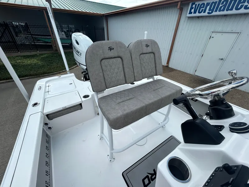 Slide: The Image of 2025 Sea Pro 230 Bay boat with open storage compartments and motor, parked outdoors. - 10