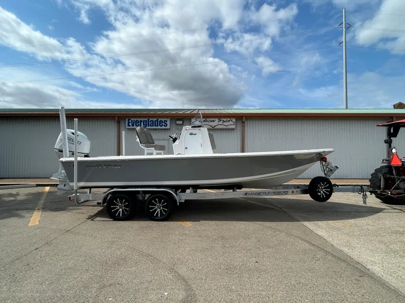 Slide: The Image of 2025 Sea Pro 230 Bay boat on trailer, parked outdoors under clear blue sky. - 4