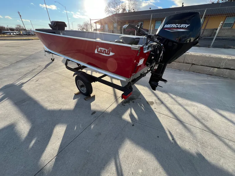 Slide: The Image of 2025 Lund 1600 Fury Tiller boat with Mercury engine on trailer, parked outdoors. - 3