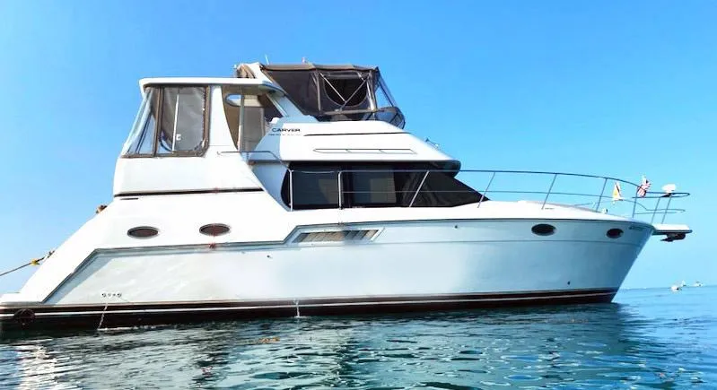 Slide: The Image of 1999 Carver 356 Aft Cabin Motor Yacht on calm water, side view. - 0