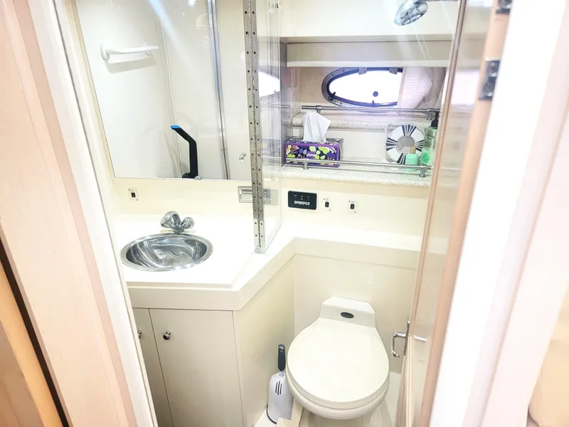 Slide: The Image of 1999 Carver 356 Aft Cabin Motor Yacht bathroom with sink, toilet, and porthole window. - 13