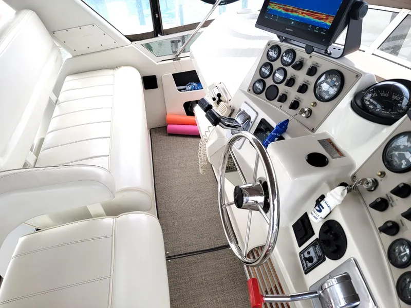 Slide: The Image of 1999 Carver 356 Aft Cabin Motor Yacht helm with white seating and control panel. - 15