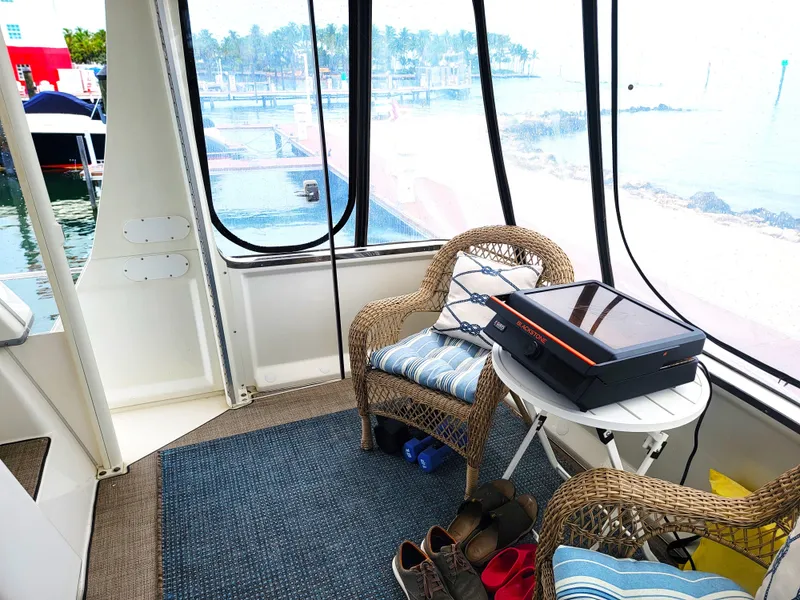 Slide: The Image of 1999 Carver 356 Aft Cabin Motor Yacht interior with wicker chairs and scenic marina view. - 20