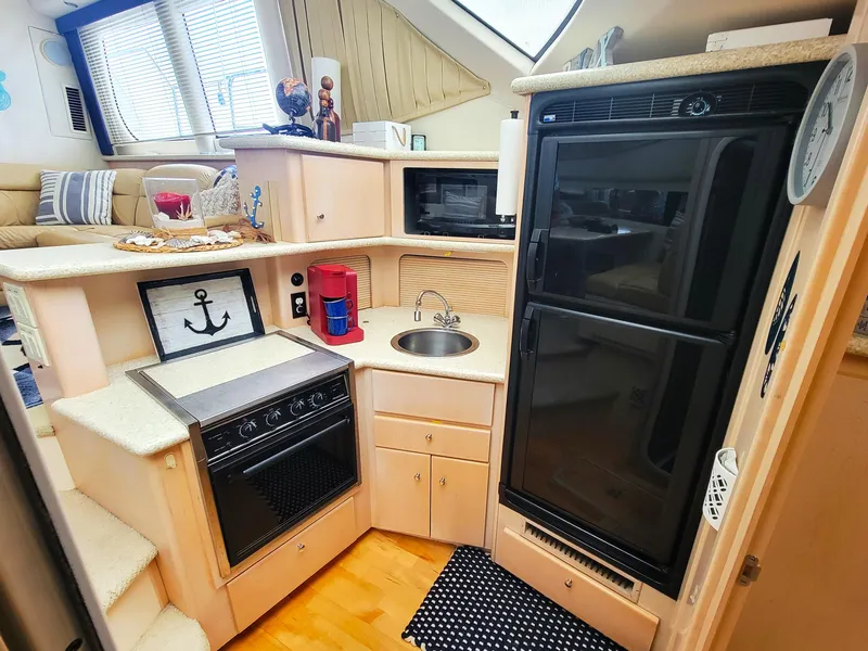 Slide: The Image of 1999 Carver 356 Aft Cabin Motor Yacht kitchen with appliances and cozy seating area. - 5