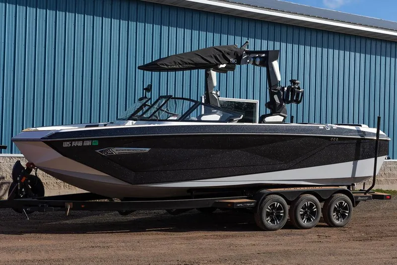 The Image of 2022 Nautique Super Air Nautique G25 boat on trailer, parked by blue building. - 0