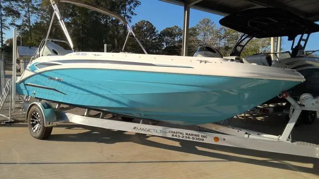 Slide: The Image of 2025 Hurricane SunDeck Sport 205 OB boat on trailer, vibrant blue hull, parked in marina. - 1