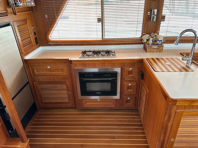 Slide: The Image of 2023 Helmsman Trawlers 43E PILOTHOUSE kitchen with wood cabinetry, stove, and sink. - 13
