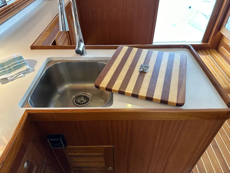 Slide: The Image of 2023 Helmsman Trawlers 43E PILOTHOUSE kitchen sink with striped wooden cover. - 18