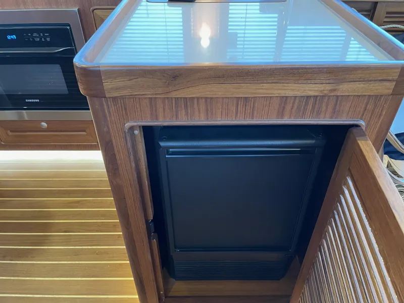 Slide: The Image of 2023 Helmsman Trawlers 43E Pilothouse interior with wooden cabinetry and modern appliances. - 21