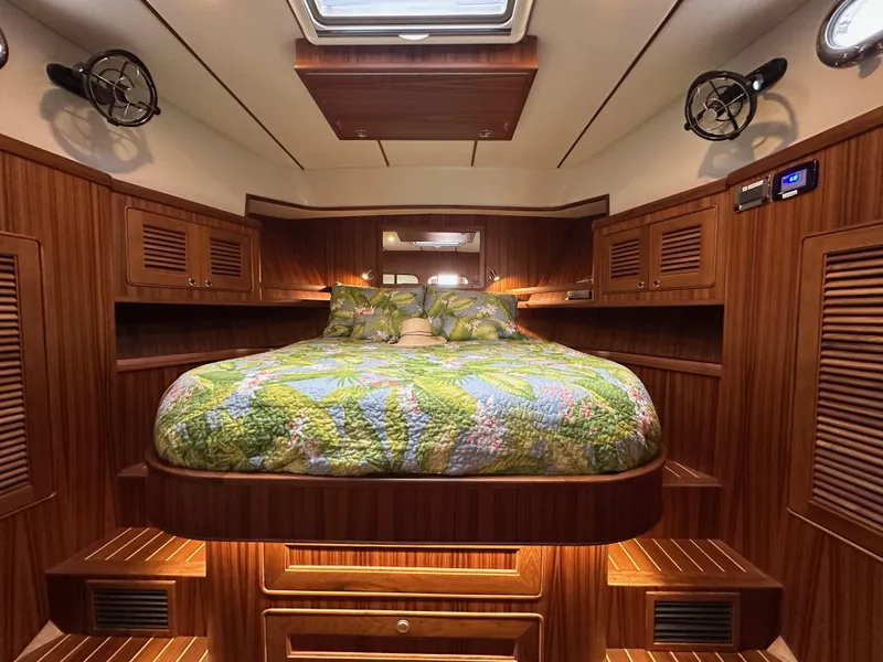 Slide: The Image of Luxurious cabin interior of 2023 Helmsman Trawlers 43E PILOTHOUSE with wood paneling and cozy bedding. - 25