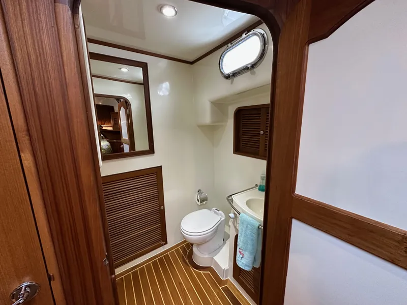 Slide: The Image of 2023 Helmsman Trawlers 43E Pilothouse bathroom with wood accents and compact design. - 31