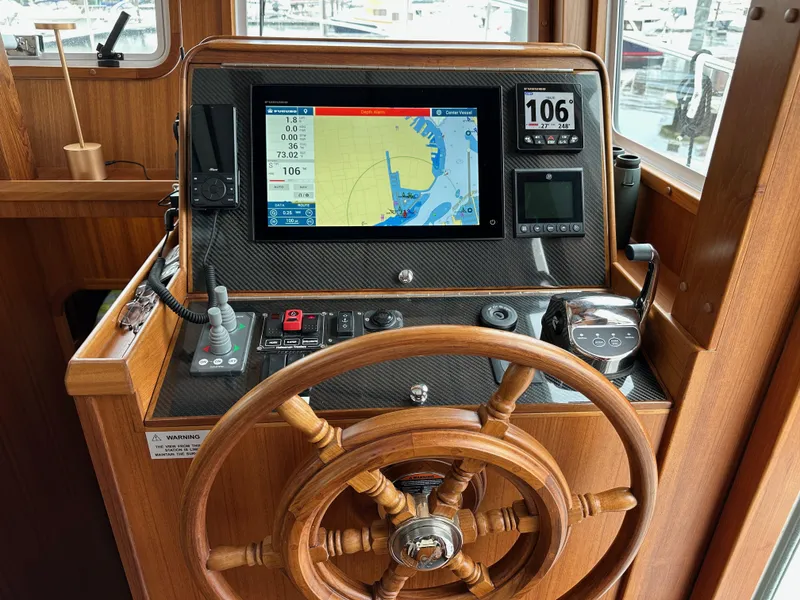 Slide: The Image of Helmsman Trawlers 43E PILOTHOUSE 2023 helm with navigation display and wooden steering wheel. - 35