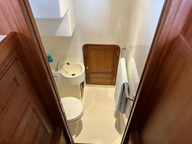 Slide: The Image of 2023 Helmsman Trawlers 43E Pilothouse bathroom with sink, toilet, and wooden cabinetry. - 38