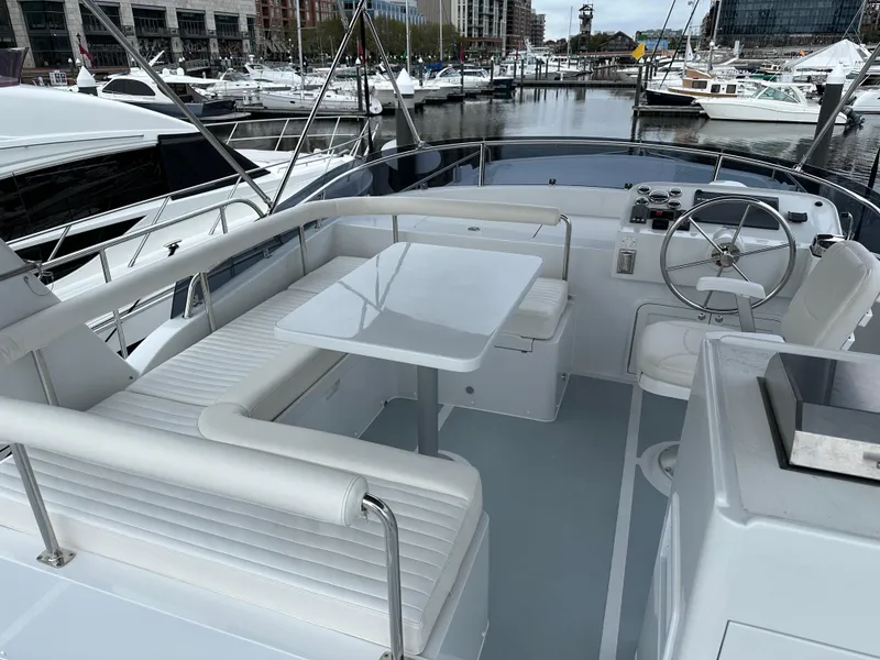 Slide: The Image of Helmsman Trawlers 43E PILOTHOUSE 2023, spacious deck with seating and table, docked in marina. - 42