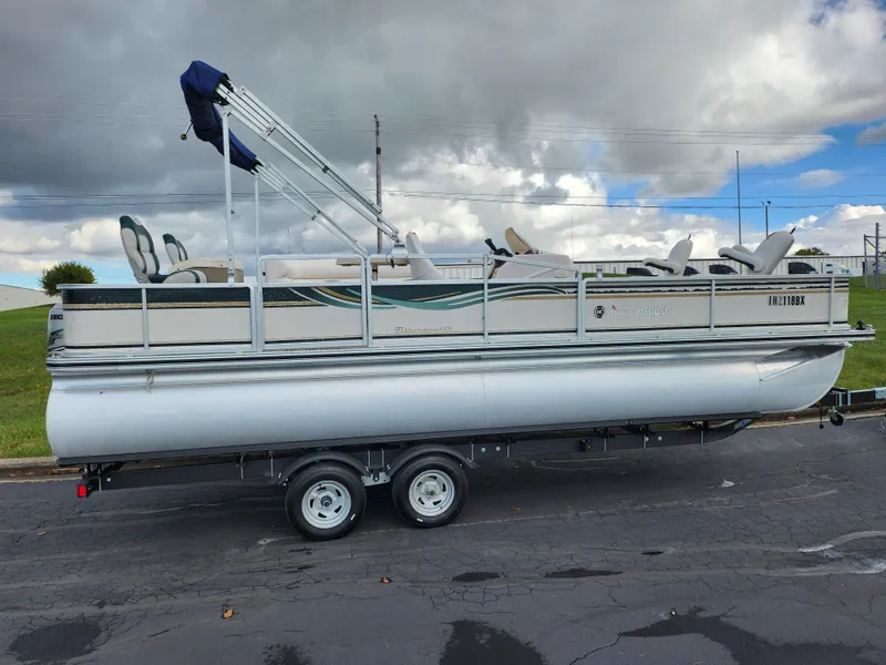 Slide: The Image of 2002 Harris FloteBote 220 Fisherman pontoon boat on trailer under cloudy sky. - 4