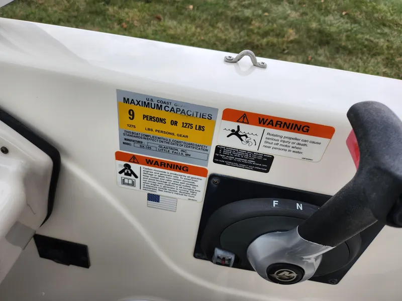 Slide: The Image of 2006 Glastron SX 195 boat capacity and warning labels near control lever. - 13