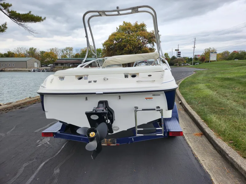 Slide: The Image of 2006 Glastron SX 195 boat on trailer by lakeside road. - 2