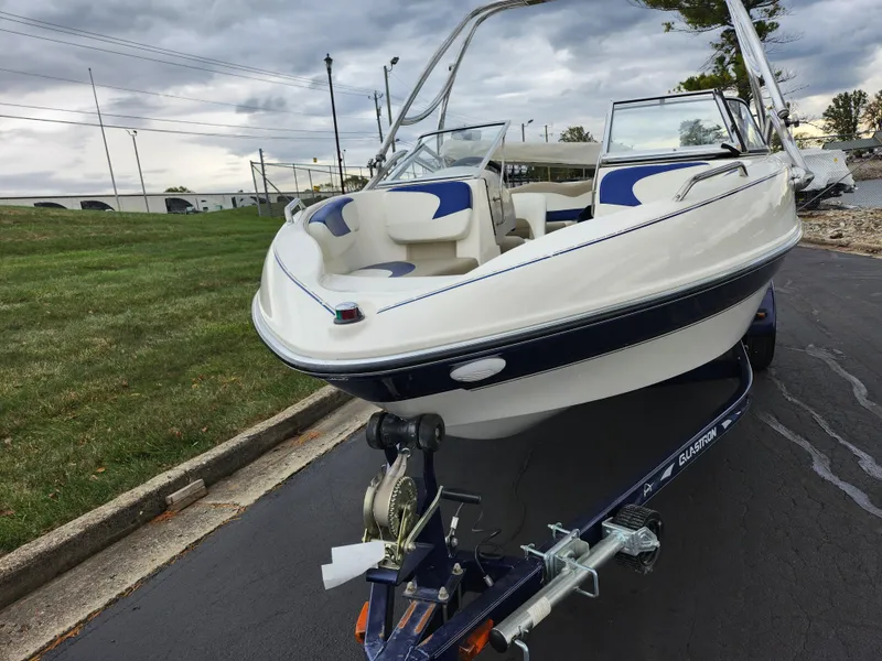 Slide: The Image of 2006 Glastron SX 195 boat on trailer, parked on paved road, cloudy sky background. - 6