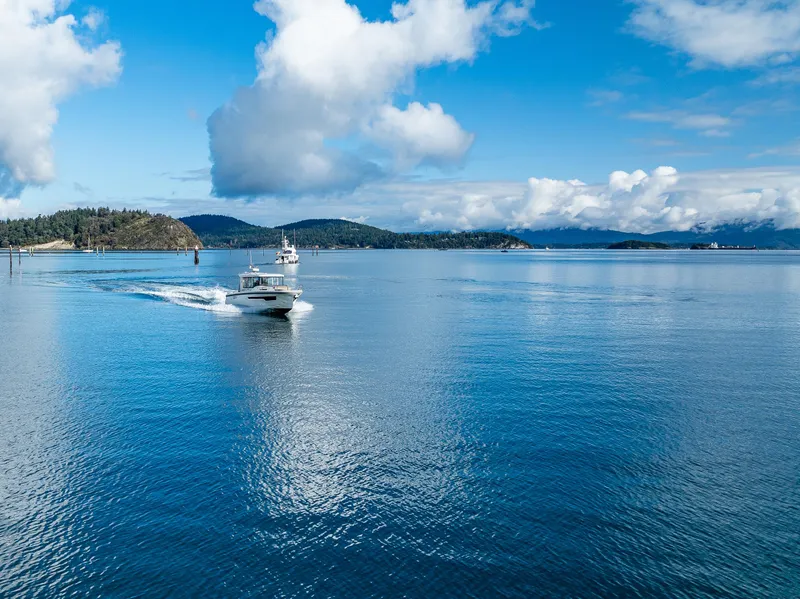 Slide: The Image of Nimbus C11 boat cruising on a serene blue lake under a partly cloudy sky. - 34