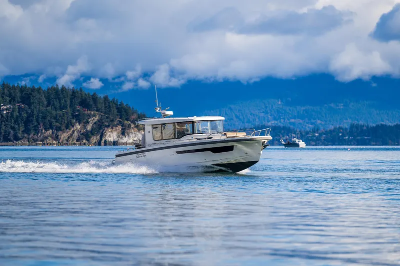 Slide: The Image of Nimbus C11 2021 boat cruising on a scenic lake with forested hills in the background. - 42