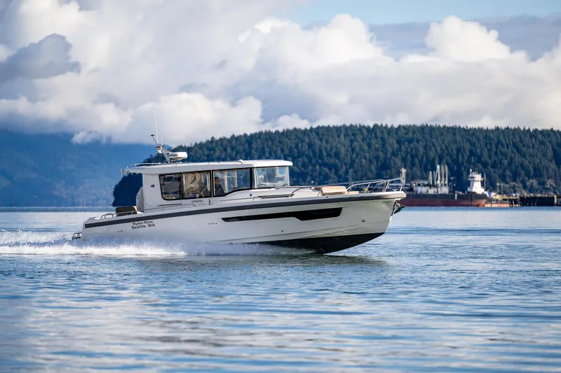 Slide: The Image of Nimbus C11 2021 boat cruising on a scenic lake with forested hills in the background. - 44