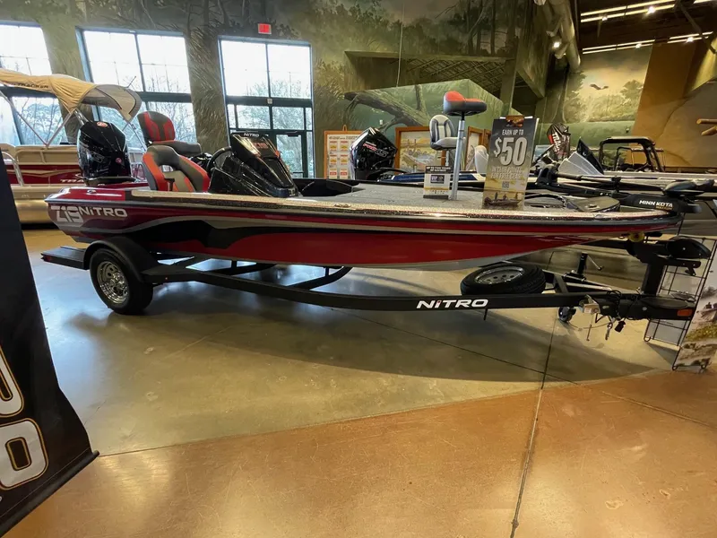 The Image of 2025 Nitro Z19 boat displayed indoors, red and black design, promotional sign visible. - 0