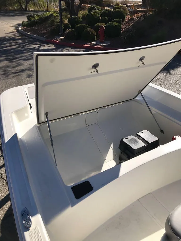 Slide: The Image of 2025 Mako Pro Skiff 17 CC boat storage compartment with open lid and battery inside. - 7