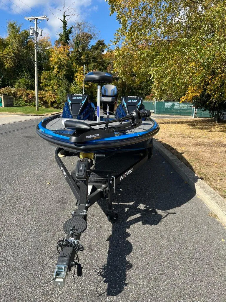 Slide: The Image of 2025 Nitro Z18 boat on trailer, parked on a sunny road with trees. - 18