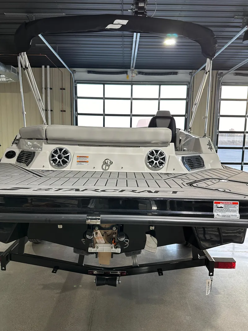 Slide: The Image of 2025 Starcraft SVX 211 IO boat in showroom, rear view with speakers and seating. - 14